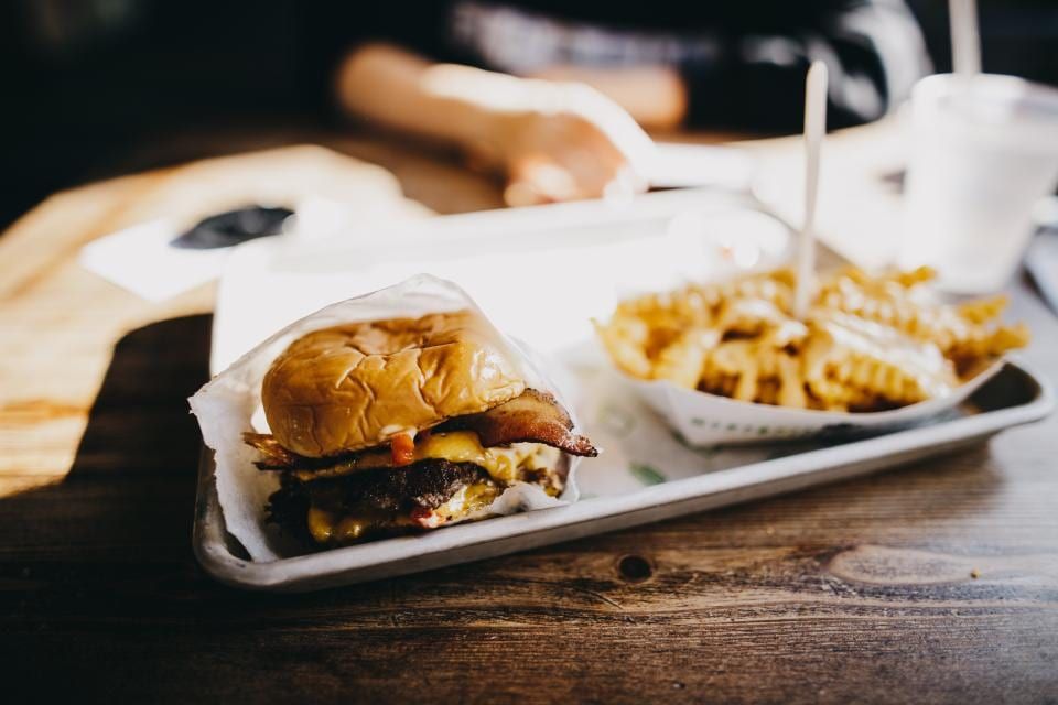 A burger and crinkle fries served on a metal tray
