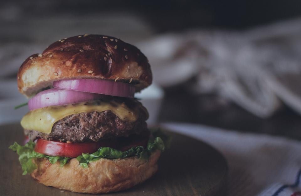 A cheeseburger with red onion on a dark table